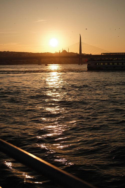 Free Serene view of a sunset over a city skyline with a bridge and calm waters. Stock Photo