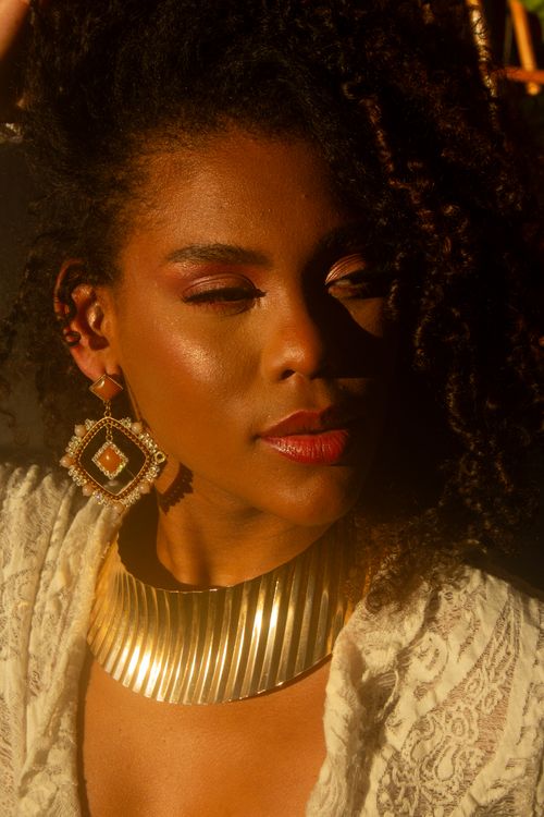 Free Close-up portrait capturing a woman's elegance with warm, golden accessories under soft light. Stock Photo