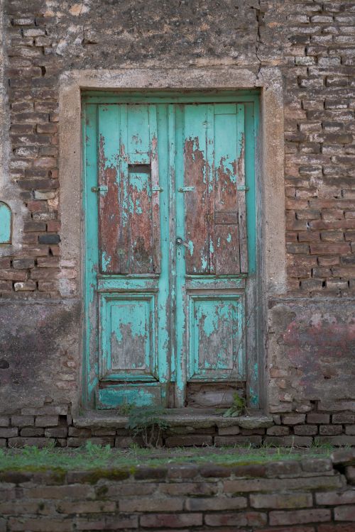 Free A weathered turquoise door in a rustic brick wall captures traditional charm in Córdoba, Argentina. Stock Photo
