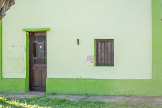 A charming rustic facade featuring a green door and window, ideal for village architecture themes.