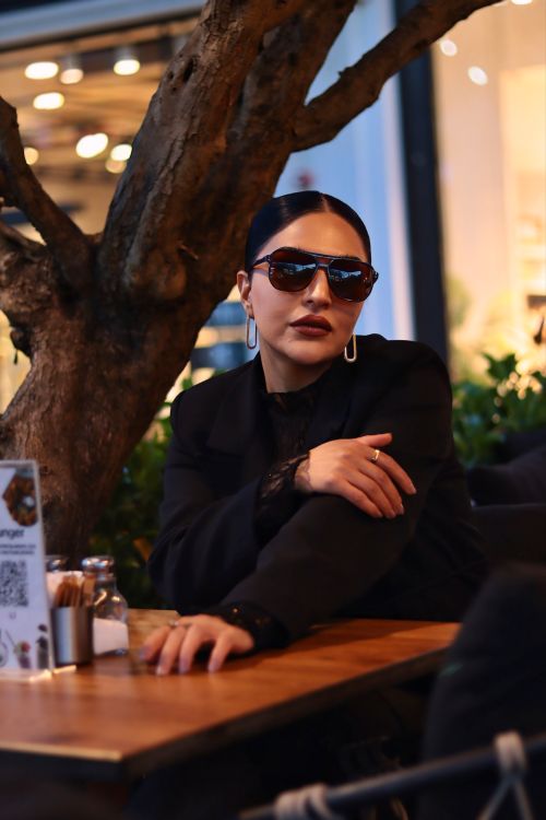 Free Chic woman in sunglasses relaxes at an outdoor café, exuding sophistication. Stock Photo