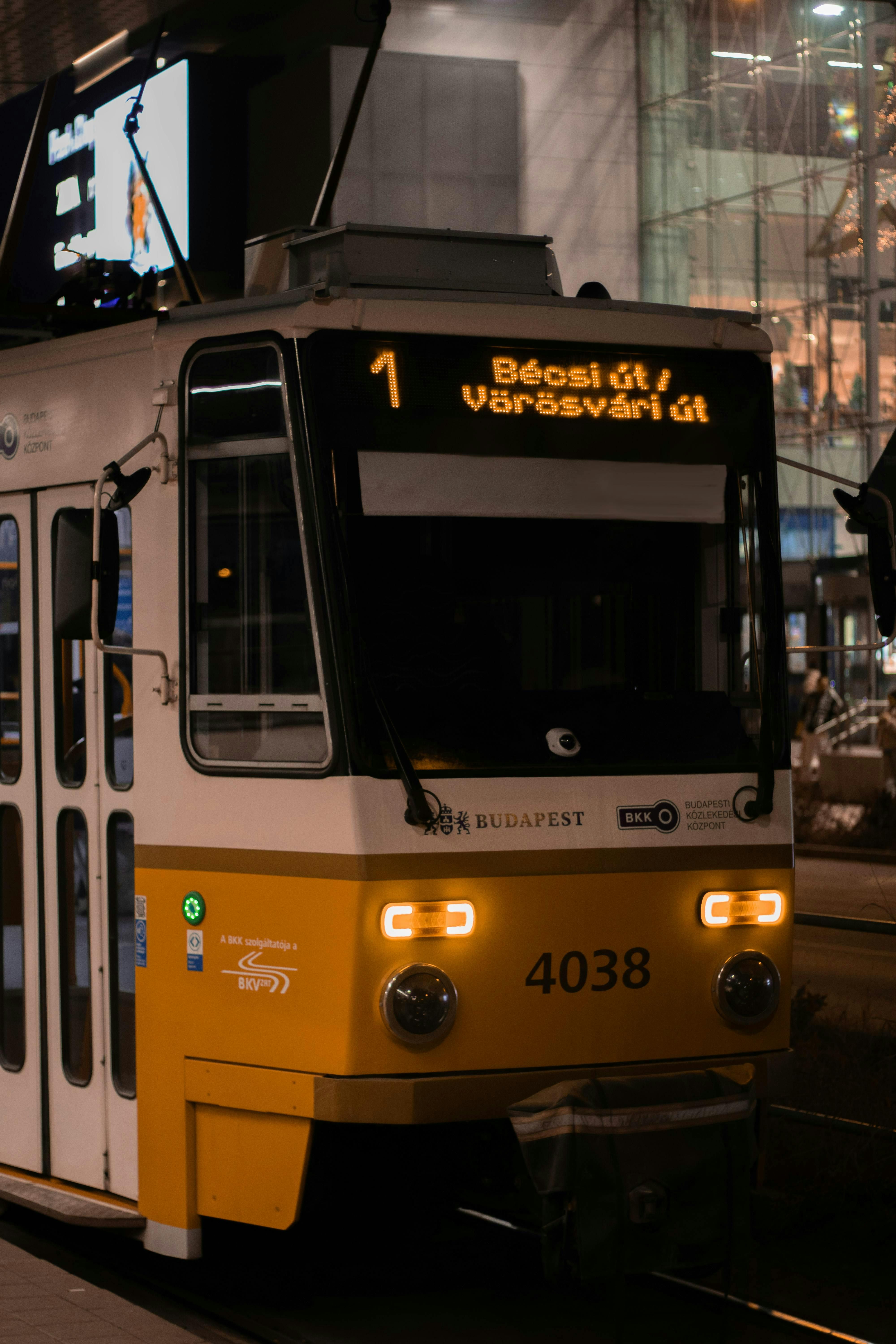A Budapest tram at night on Becsi and Vörösvári út routes with urban backdrop.