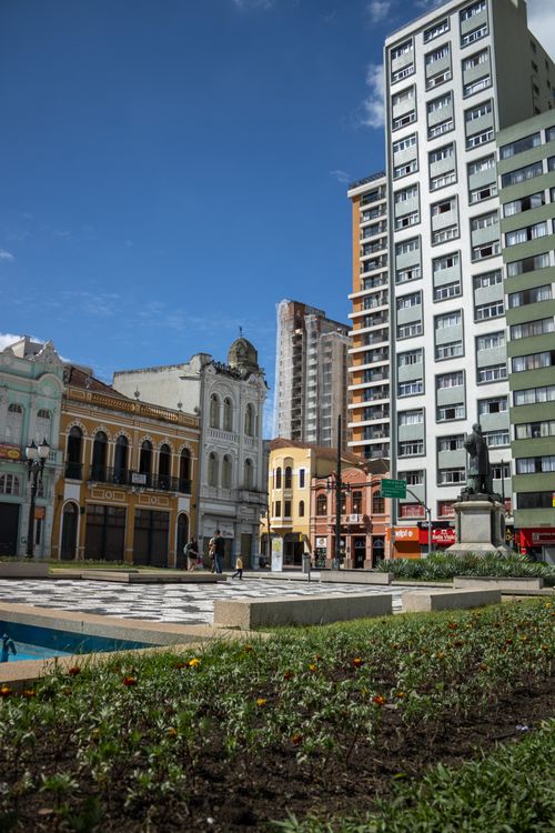 Free Bustling urban square with historic buildings and a statue, under a clear blue sky. Stock Photo