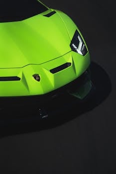 A striking close-up of a luxury green sports car's front bumper and headlights.