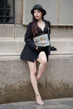 Stylish woman in black attire poses outdoors, showcasing fashion elegance.