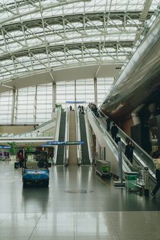 View of the interior of Seoul Incheon Airport with escalators and travelers.