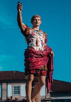 Detailed view of a Roman statue against a clear blue sky, showcasing historical artistry.