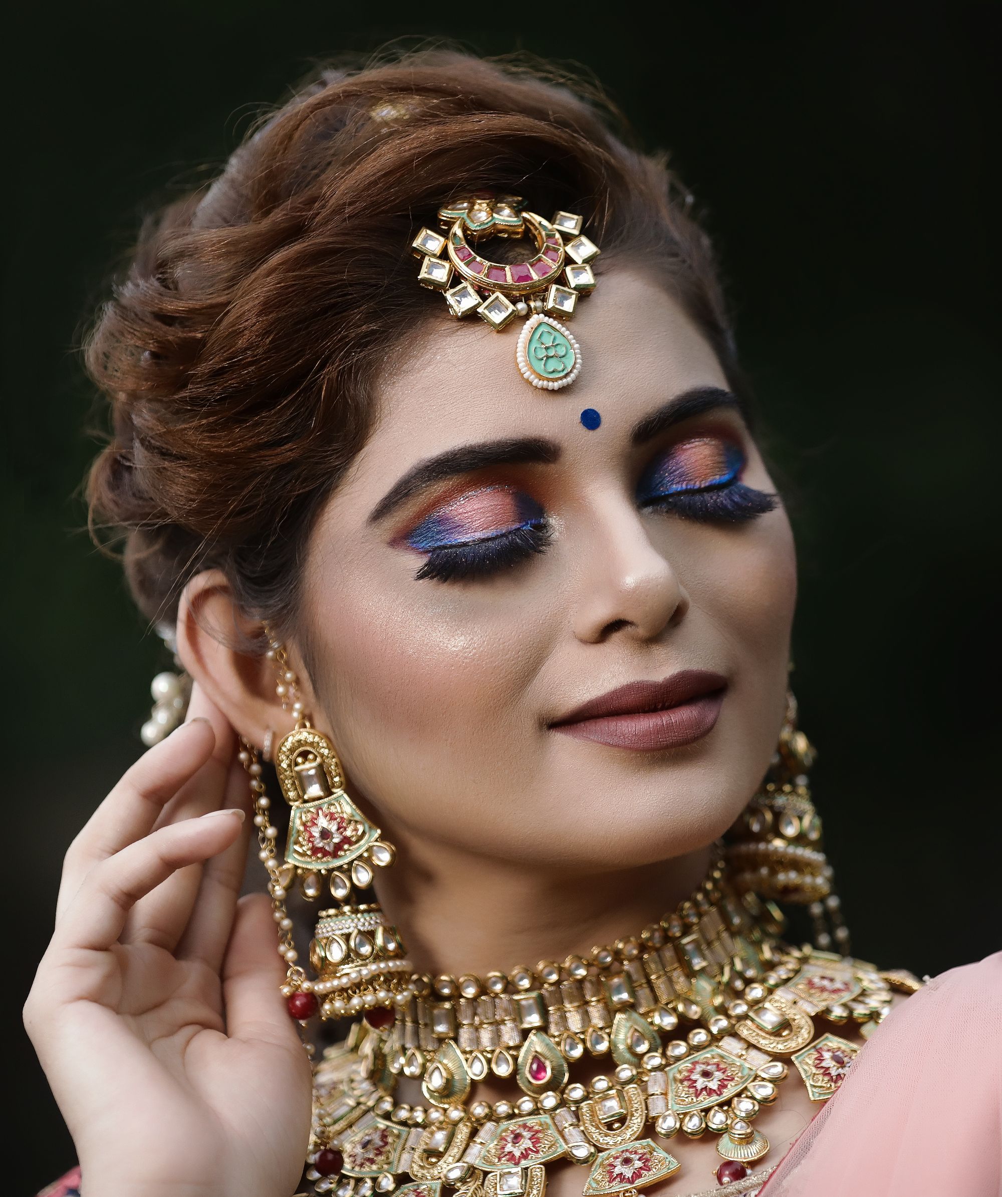 Bride wearing gold earrings and a maang tikka