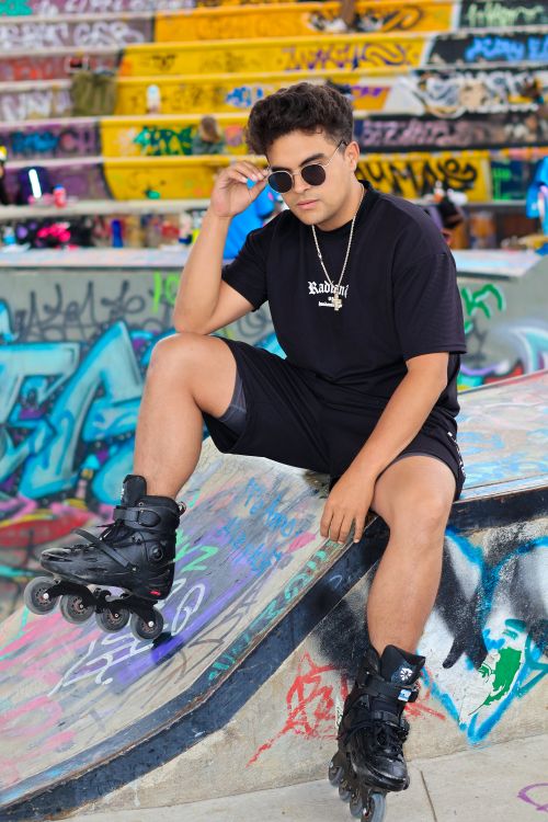 Free Confident skater in black outfit posing on colorful graffiti ramp outdoors. Stock Photo