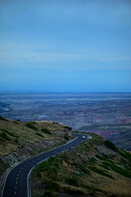 A picturesque winding road through a vast mountainous landscape under a clear blue sky.
