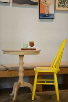 A charming cafe corner with a yellow chair and wooden table, perfect for socializing.