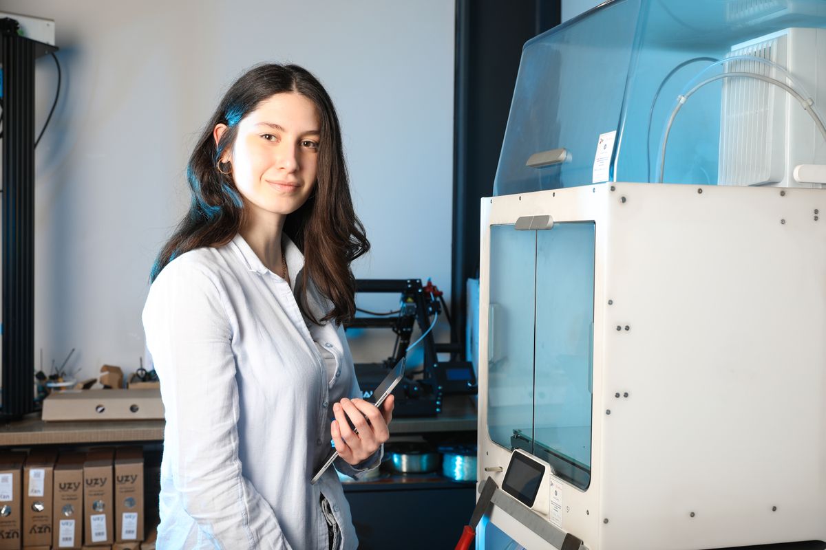 Female engineer holding a tablet beside a 3D printer in a modern workshop