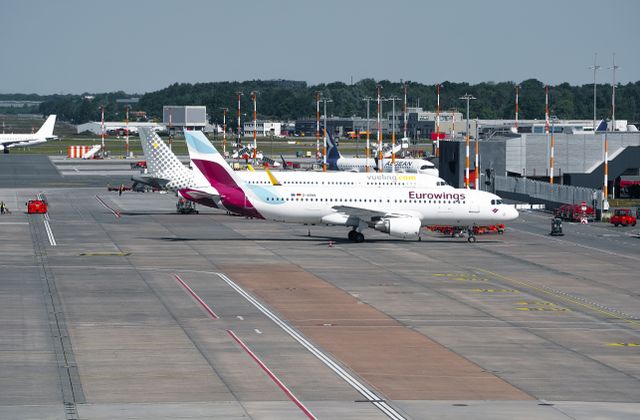 Wide-angle view of a bustling airport in Hamburg featuring Eurowings aircraft on the taxiway. — arriving in Hamburg