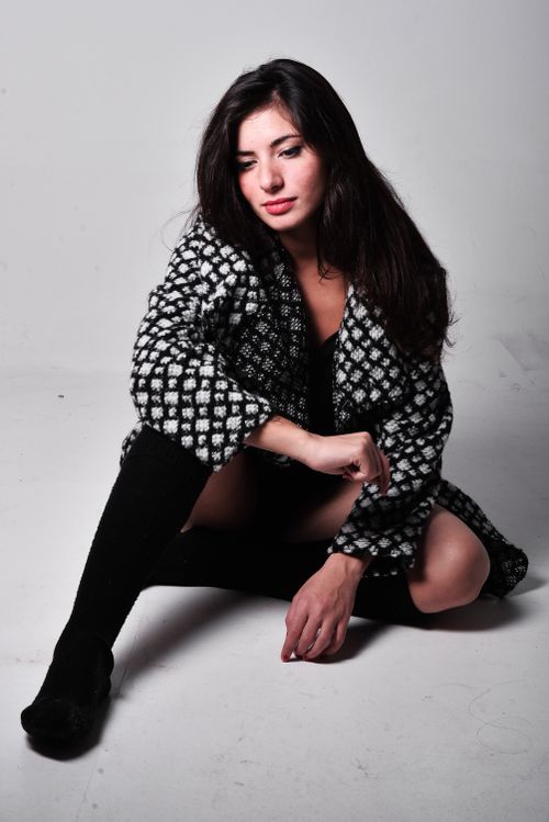 Free Fashionable woman sitting on the floor modeling a black and white checkered coat. Stock Photo