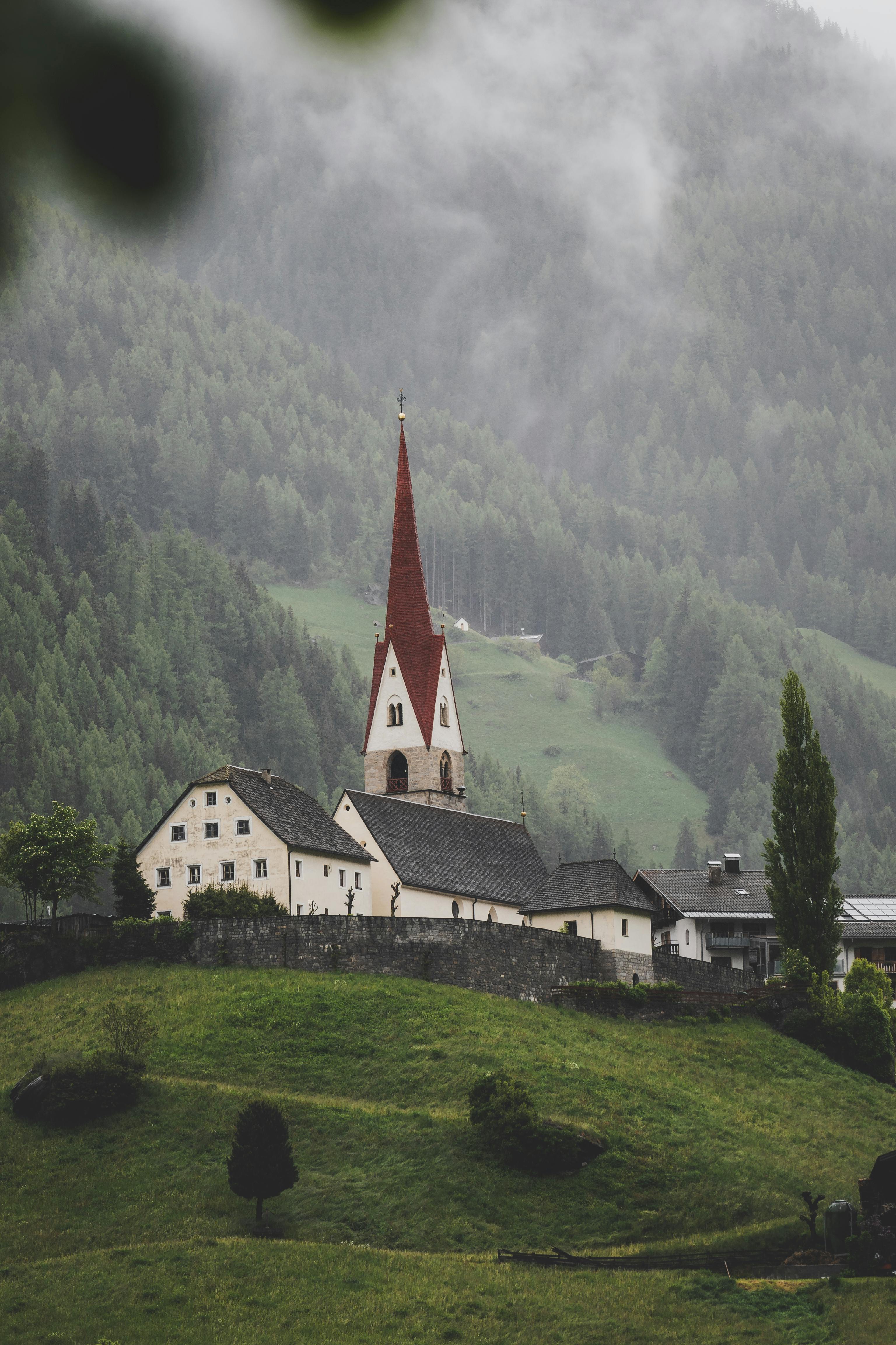 Picturesque Alpine village with iconic church and misty hills in the background.