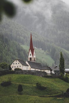 Picturesque Alpine village with iconic church and misty hills in the background.