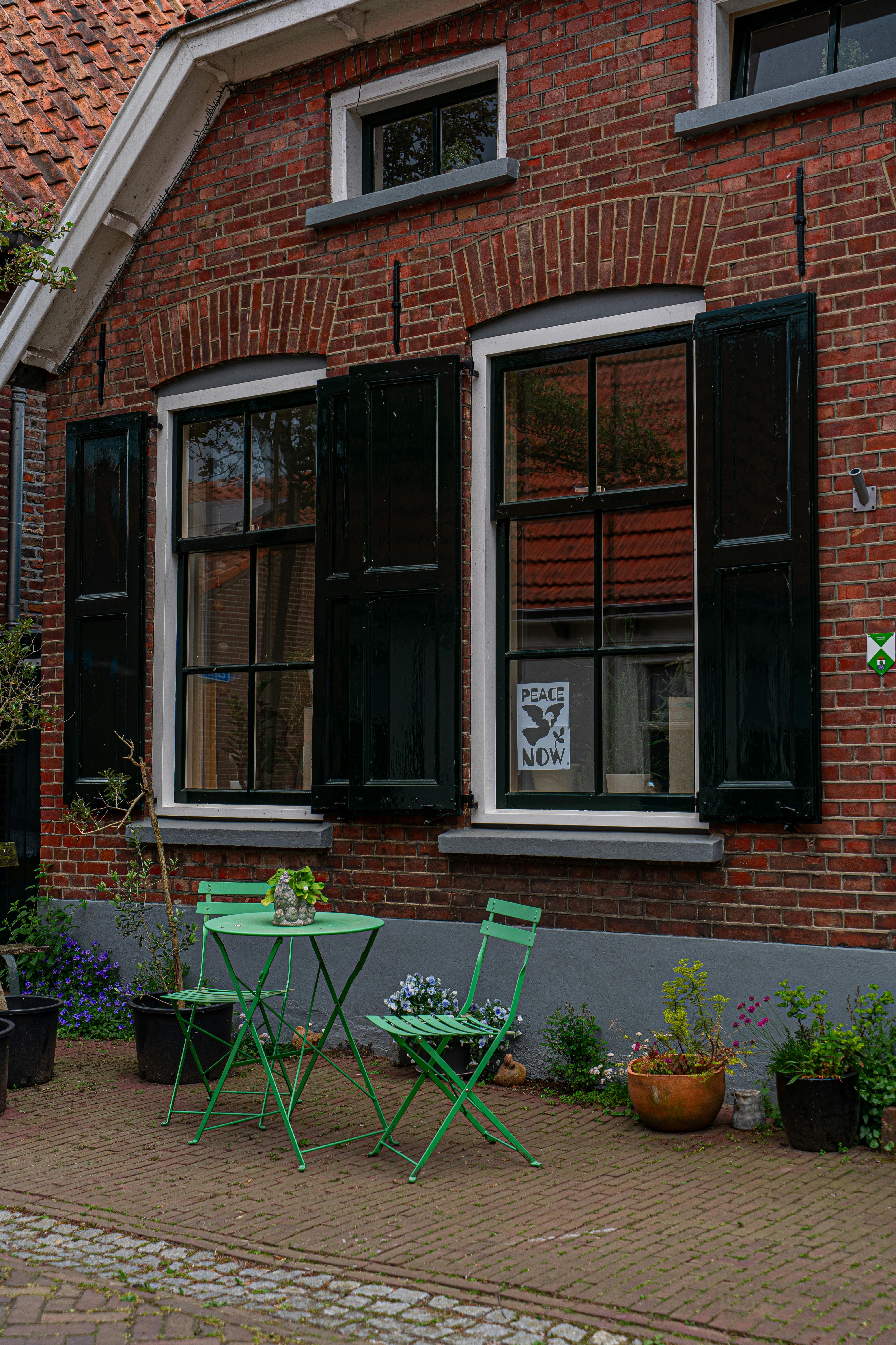 A cozy scene with a brick house and vibrant green garden furniture, perfect for outdoor relaxation.