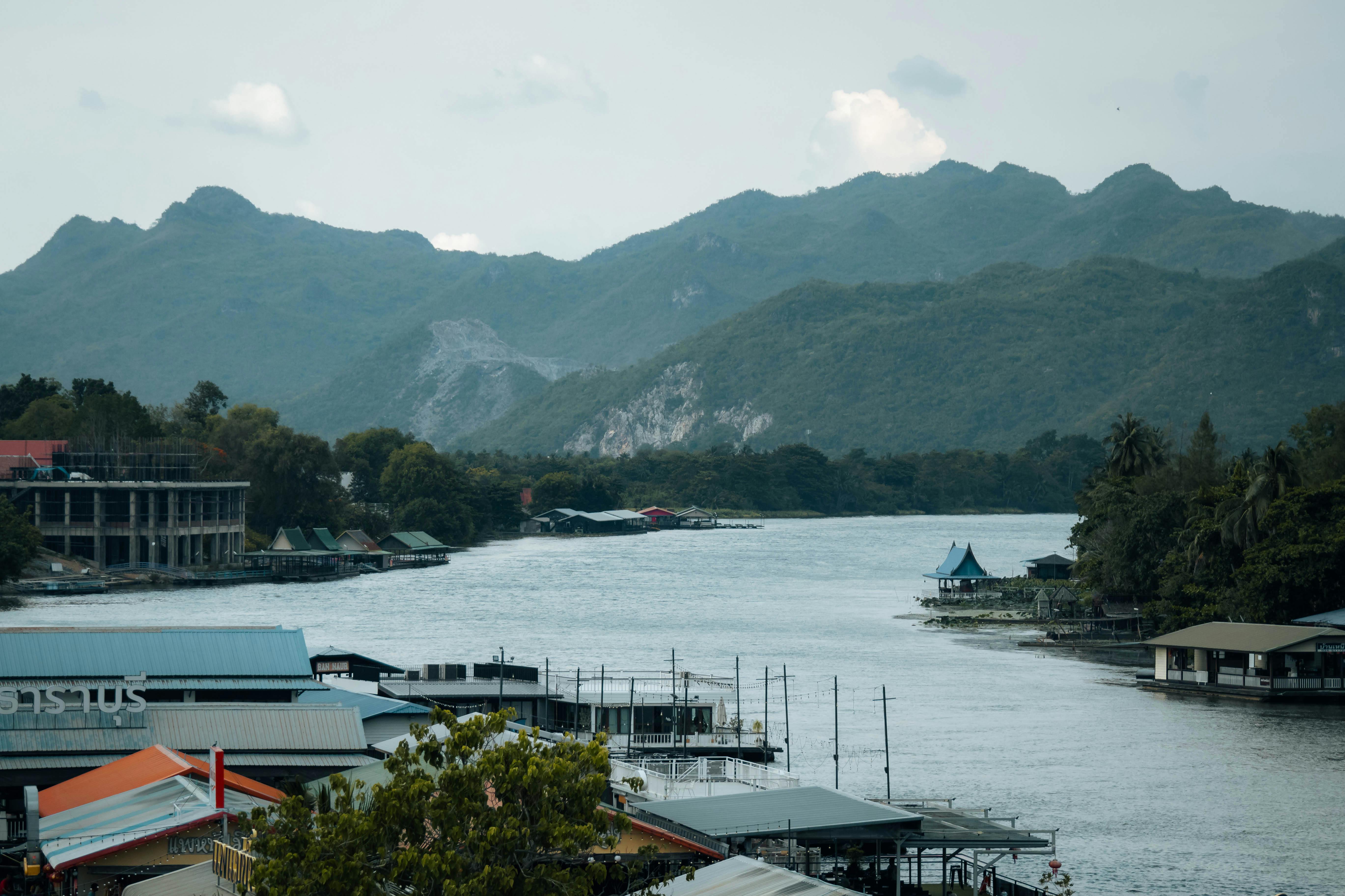 Picturesque view of the riverside in Kanchanaburi, Thailand, with mountains in the background. - Kanchanaburi