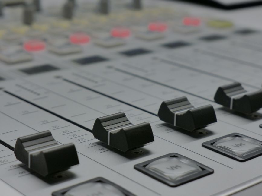 Detailed view of audio mixer sliders in a recording studio setting.