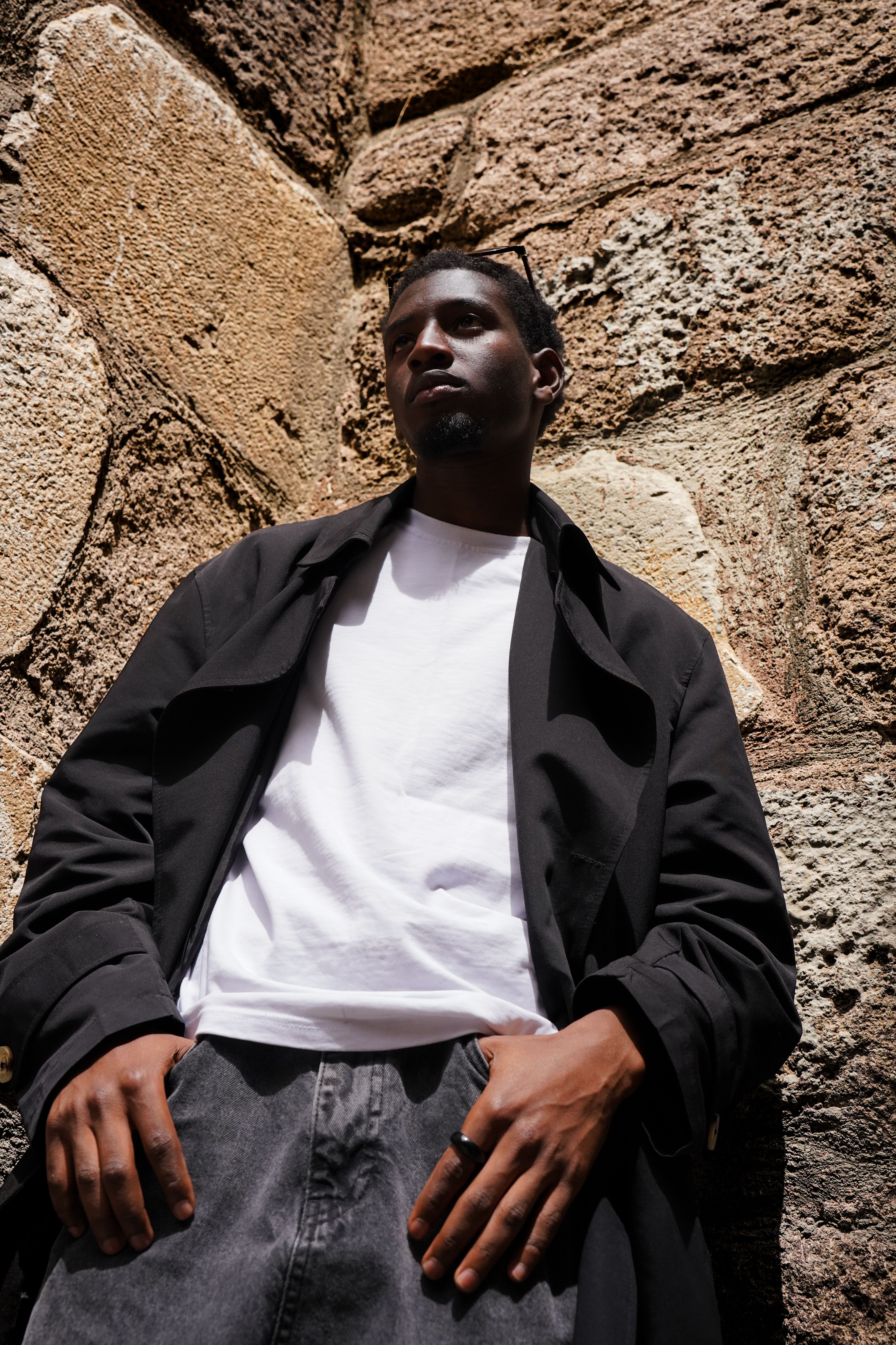 Fashionable young adult posing against a rustic stone wall in Ankara, Türkiye.