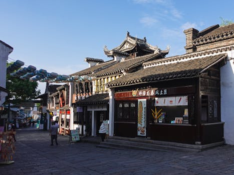A picturesque street in China with traditional architecture and vibrant shops under a clear blue sky.