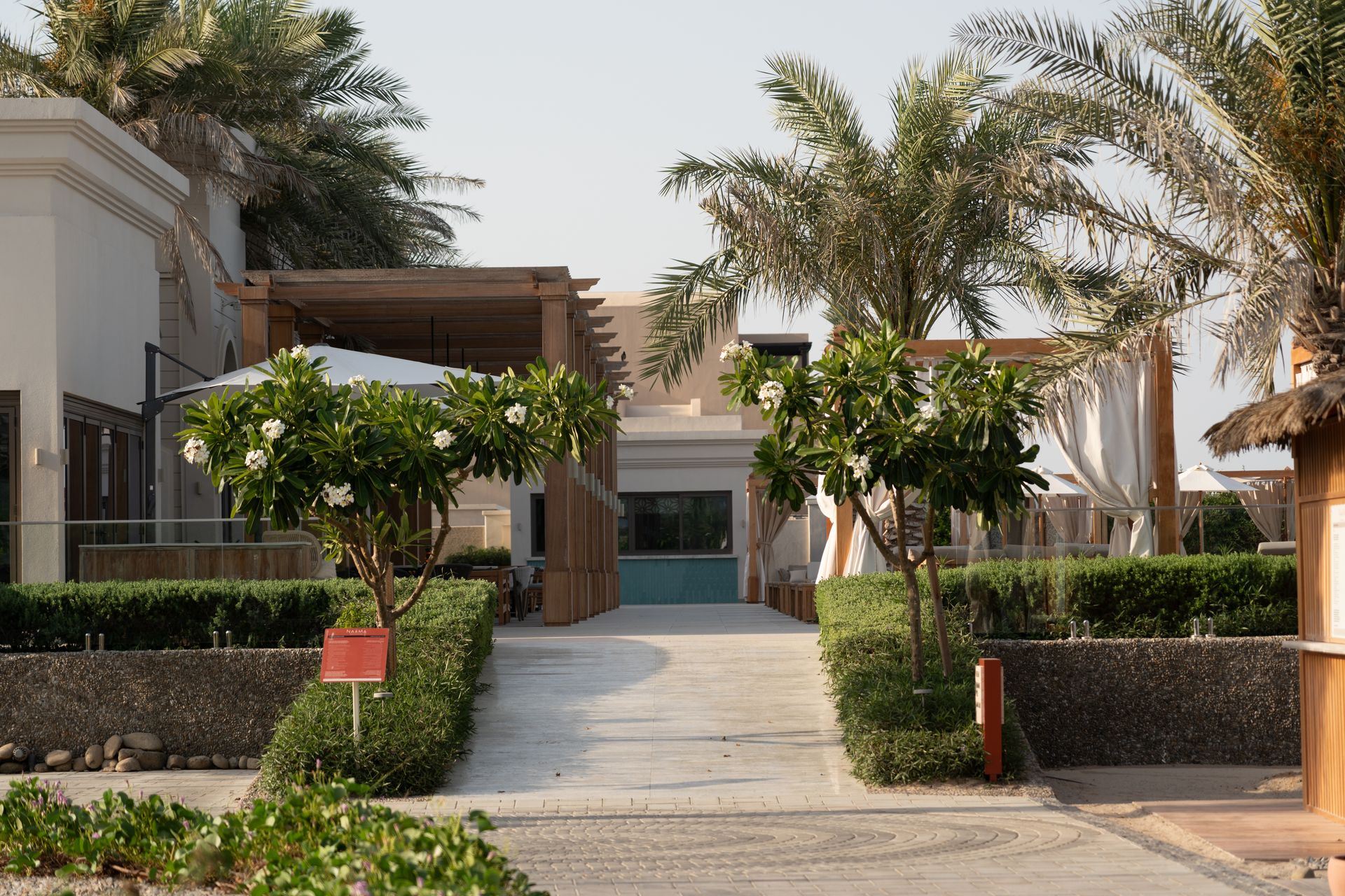 A serene pathway through a luxury Dubai resort featuring lush palm trees and elegant architecture.