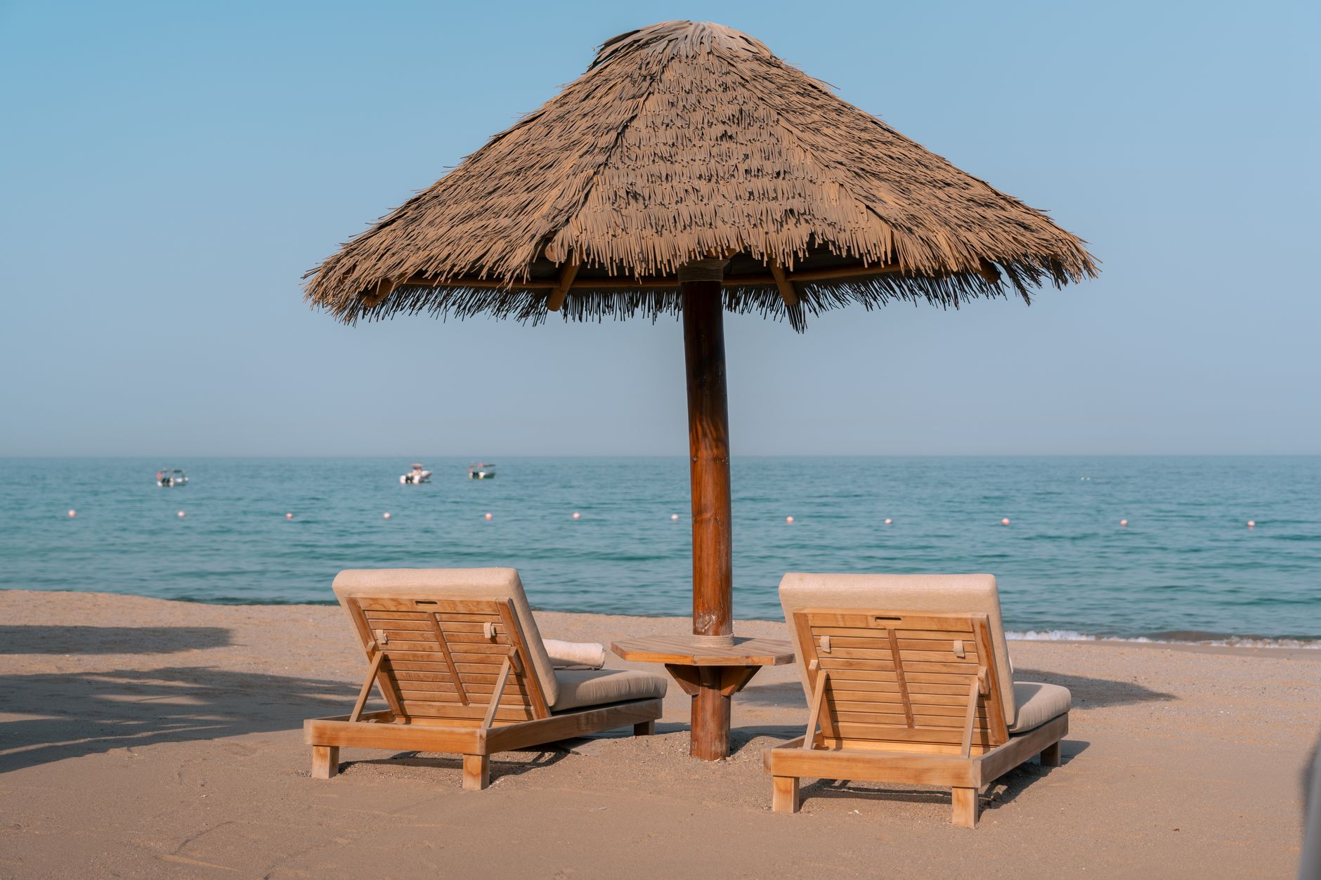 Serene beach setting in Dubai with lounge chairs and a thatched umbrella by the sea.