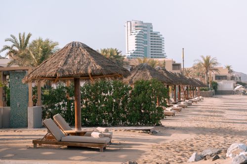 Free Stunning beachfront resort view with sun loungers and wooden huts in Dubai. Stock Photo