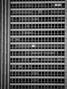 Monochrome view of a skyscraper façade with uniform windows creating a geometric pattern.