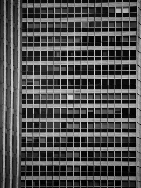 Monochrome view of a skyscraper façade with uniform windows creating a geometric pattern.