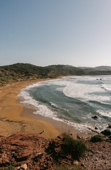 Picturesque Cala Pilar Beach in Menorca with stunning coastline views and clear blue waters.