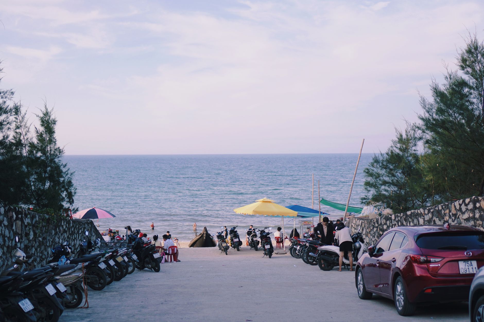 Beach entrance in Vietnam with motorbikes and people enjoying a sunny day. Scenic view of the ocean.