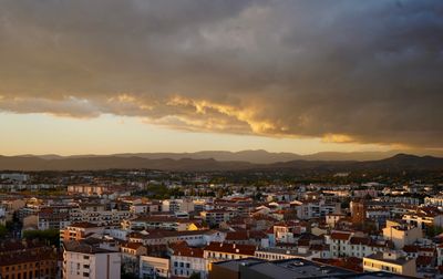 Un paysage urbain époustouflant sous un ciel de coucher de soleil spectaculaire avec des nuages pittoresques et des montagnes lointaines.