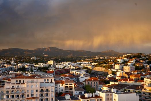 A breathtaking view of the city at sunset with mountains and dramatic skies.
