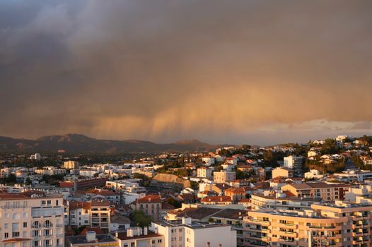 A cityscape view captures dramatic storm clouds and sunset hues, creating a striking scene.