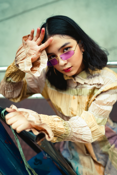 一位时髦的女人戴着充满活力的紫色太阳镜，坐在户外，身边放着葡萄酒装备