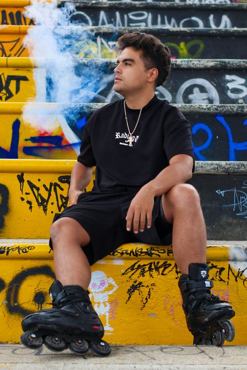 Free Young man on rollerblades sits on graffiti-covered steps with smoke in the air, creating a vibrant urban scene. Stock Photo