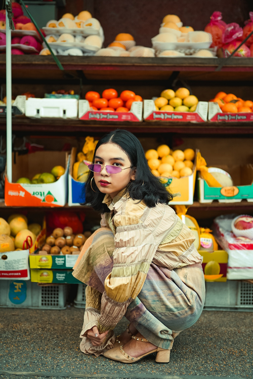 Free Stylish woman in colorful outfit posing at a lively fruit market stall. Stock Photo