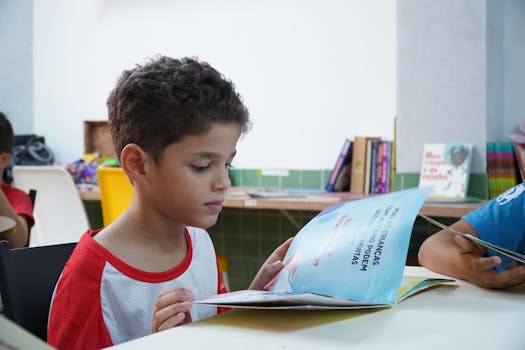 A young boy engrossed in reading a book in a classroom environment, promoting child literacy.