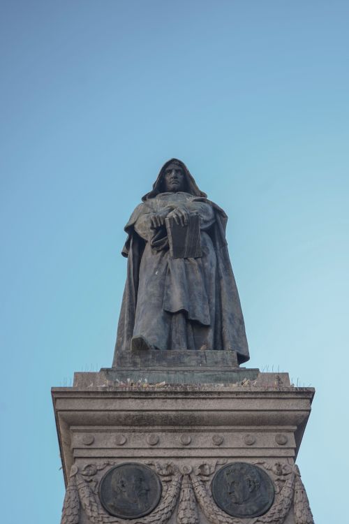 Free Classic statue of Giordano Bruno in Rome's Campo de' Fiori against a clear blue sky. Stock Photo