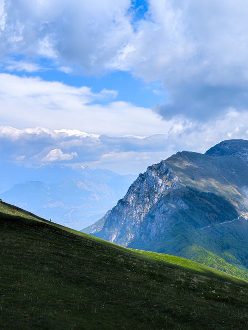 Free Majestic mountain landscape with vibrant green hills under a dramatic sky. Stock Photo