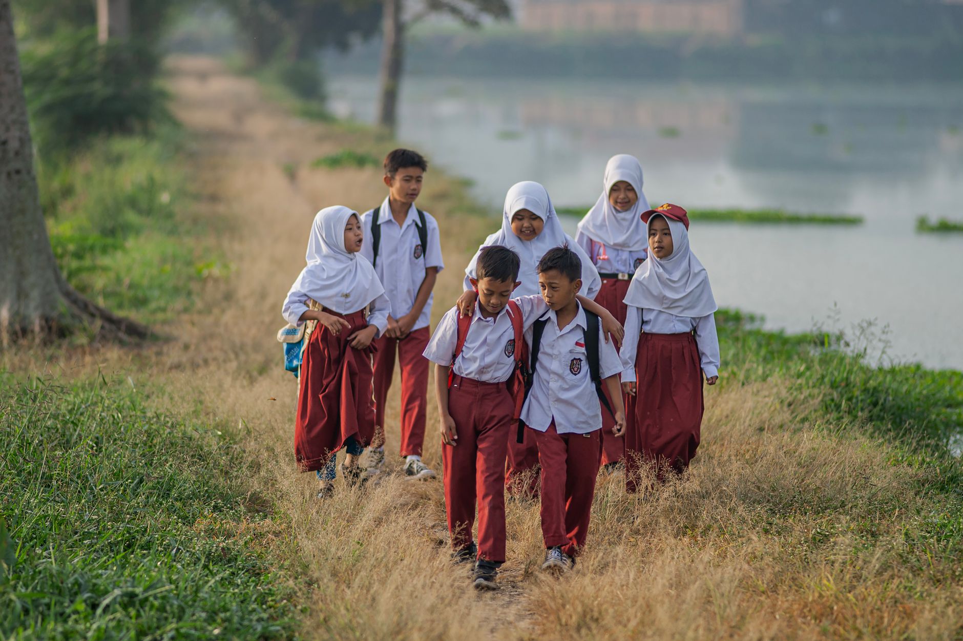 Group of children in school uniforms walking along a rural path in West Java, Indonesia.