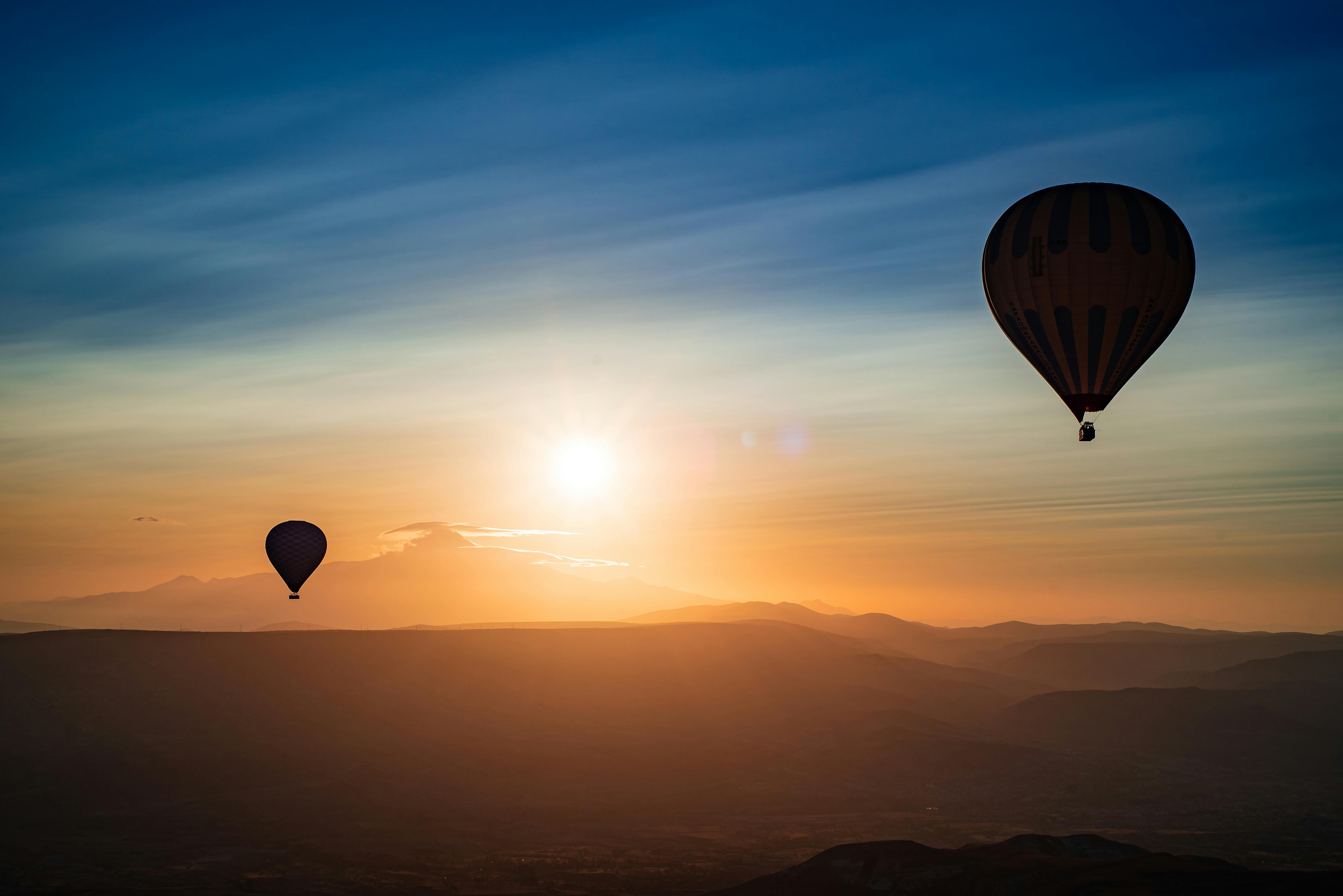 Captivating view of hot air balloons during sunrise over the scenic landscapes of Cappadocia, Türkiye.