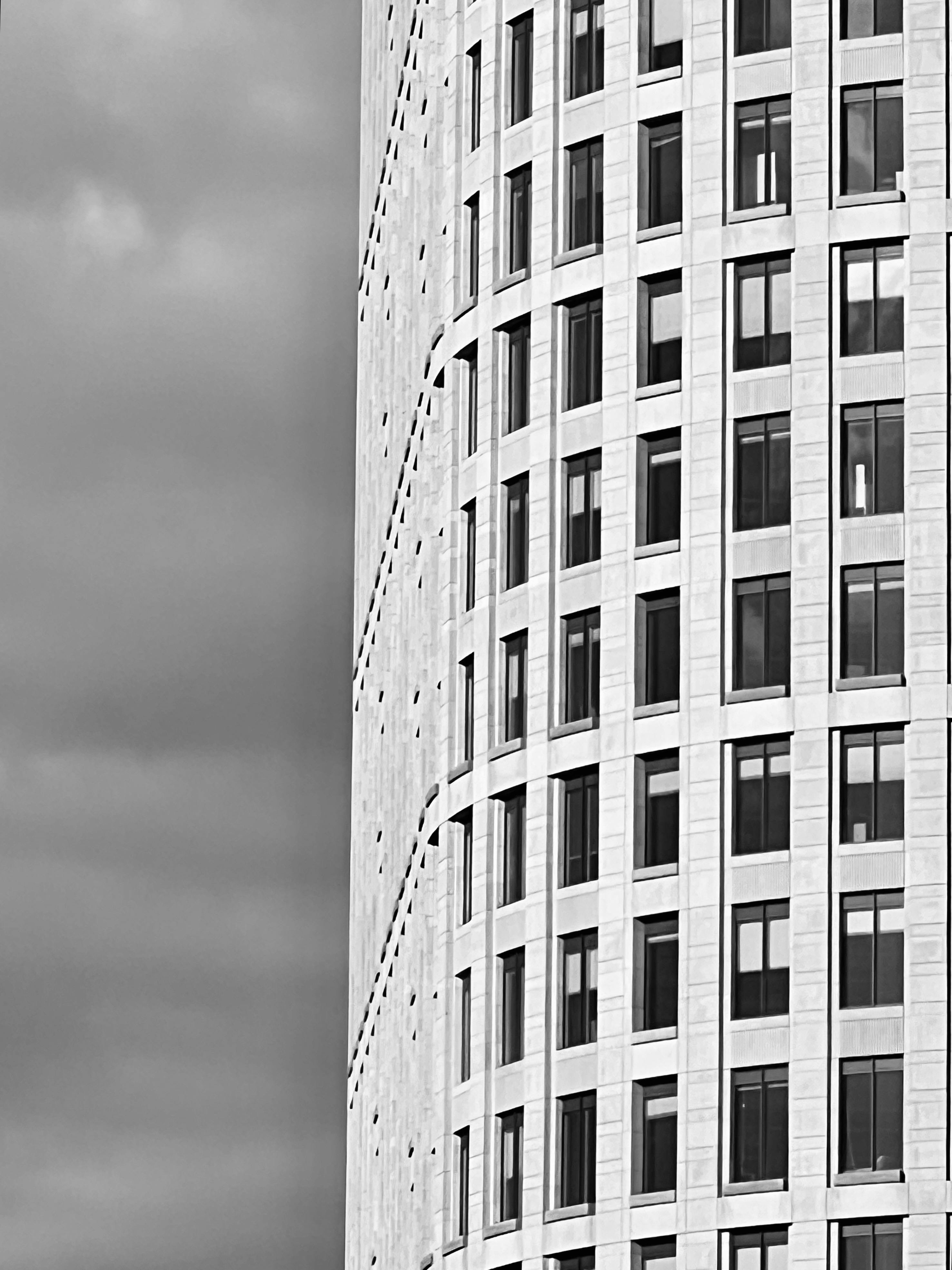 Kostnadsfria Svartvitt foto av en modern, välvd byggnadsfasad med många fönster och minimalistisk design. Stock foto