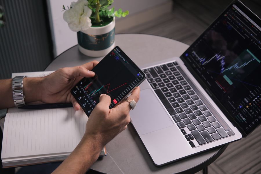 Investor reviewing stock market information on a laptop and phone