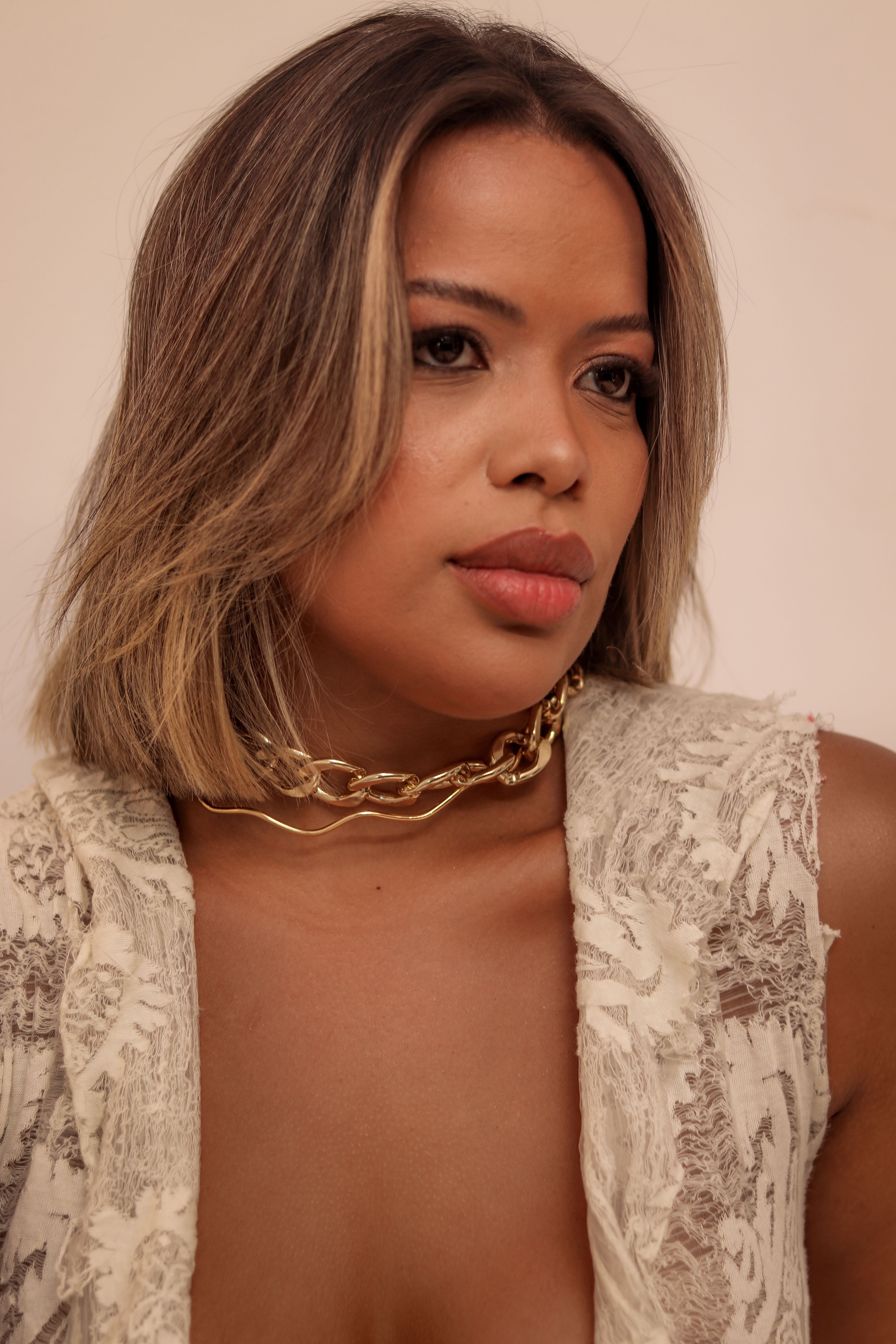 Portrait of woman in lace dress and gold necklace, exuding elegance and style.