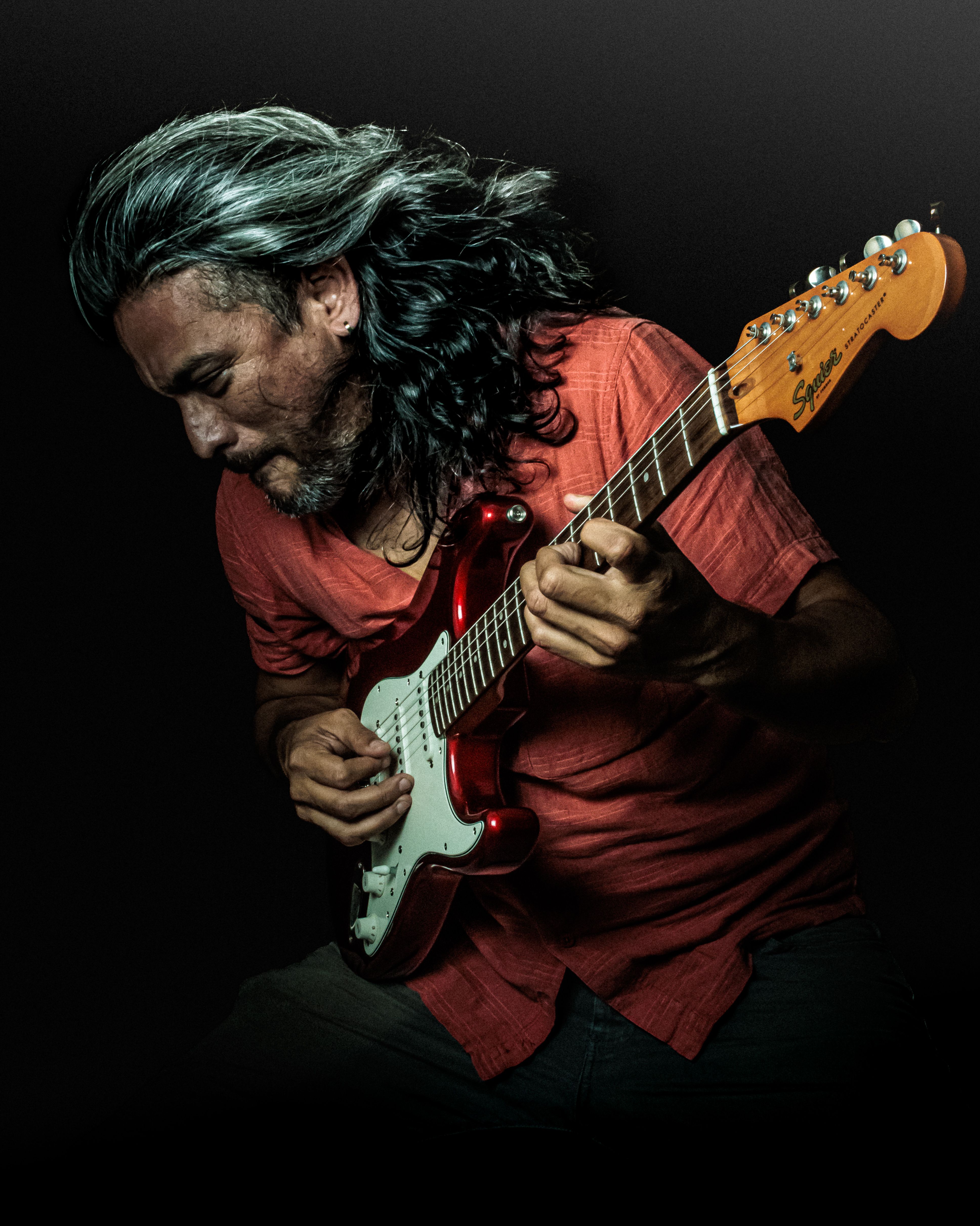 Dynamic portrait of a man passionately playing an electric guitar in dramatic lighting.