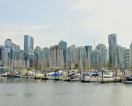 Vancouver marina against a backdrop of skyscrapers, showcasing urban waterfront life.