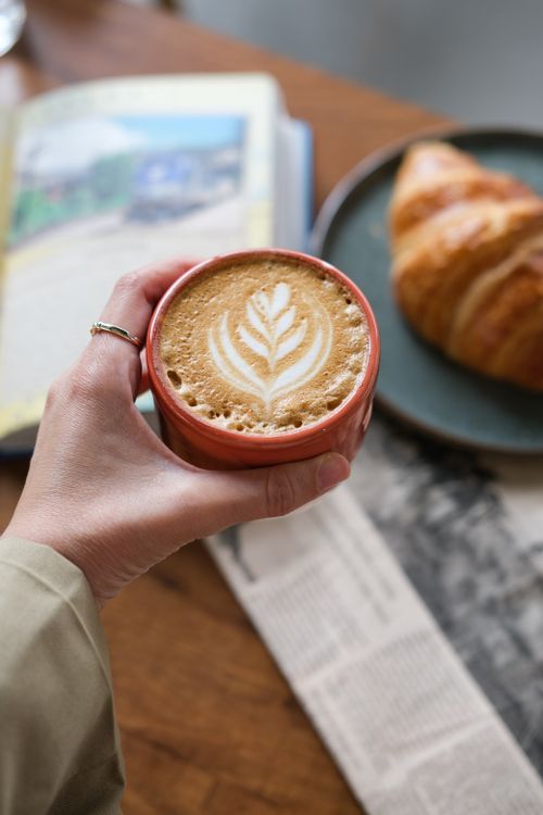 Free Enjoy a morning coffee with intricate latte art alongside a fresh croissant. Stock Photo