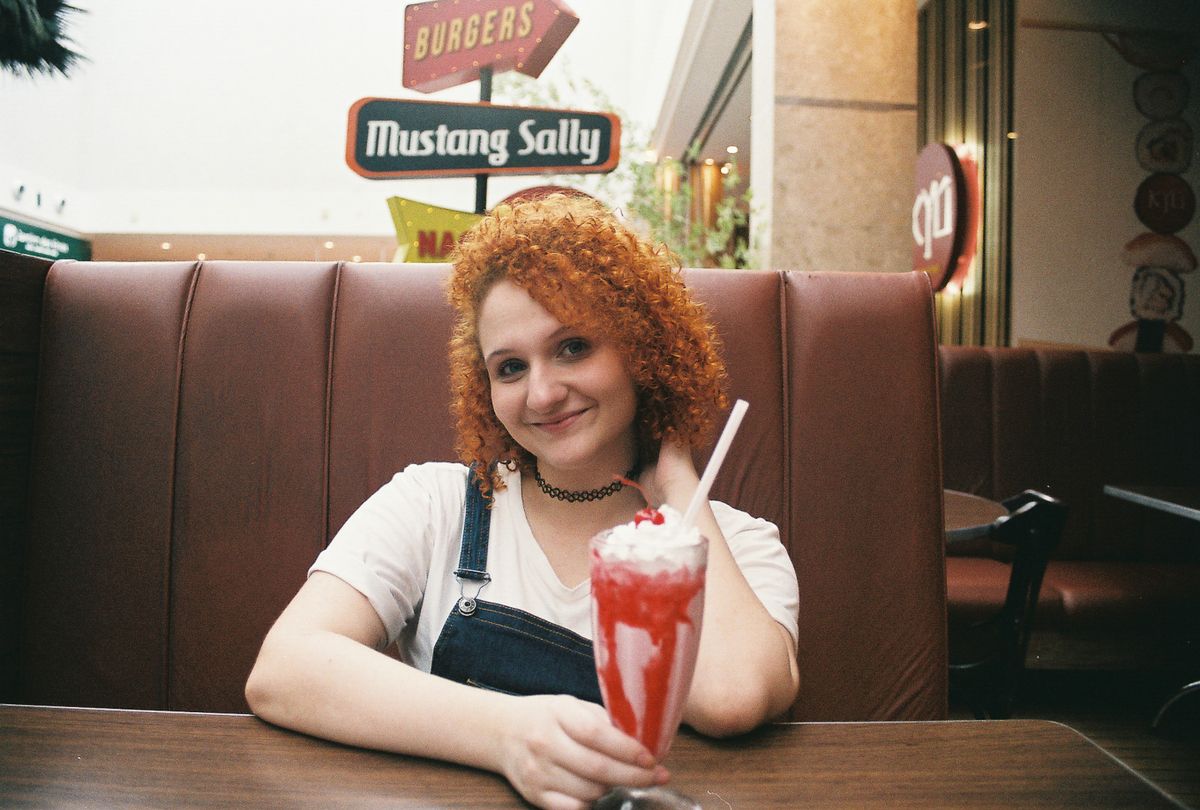 Young woman enjoying a classic strawberry milkshake in a retro diner booth